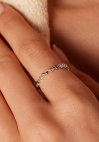 Zilveren ring met afwisselende bladvormige accenten en kleine heldere stenen, met een gladde, gepolijste afwerking en een verfijnd ontwerp.