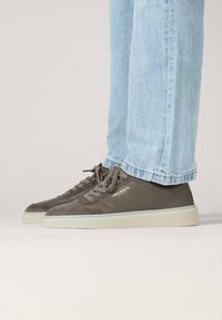 Grijze lage sneakers met een bovenwerk van suede en leer, ronde neus, contrasterende witte zool en logo-detail aan de zijkant.