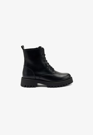 Bottine en cuir noir avec bout arrondi, fermeture à lacets à l'avant et semelle en caoutchouc épaisse à motif rainuré. Texture lisse, accents minimaux.