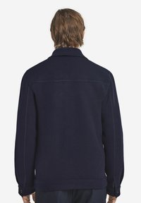 Marinblå ullblandad jacka med krage, skräddarsydd passform, sidofickor, knappmanschetter och kontrasterande sömnadsdetaljer.