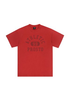Czerwona bawełniana koszulka z krótkim rękawem, okrągłym dekoltem i ciemnym nadrukiem z napisem "ATHLETIC 99 PROSTO" w pogrubionej czcionce na przodzie.