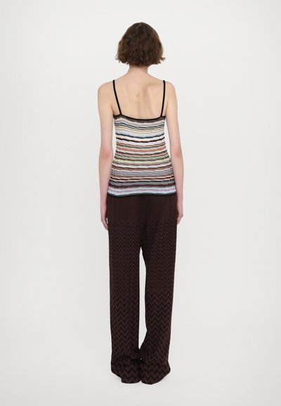 Multicolored sleeveless top with horizontal stripes, paired with wide-leg brown zigzag patterned pants. Soft, lightweight fabric.