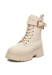 Beżowy botek na sztucznej skórze z przodu na sznurowadła, regulowany pasek z klamrą, masywna podeszwa na platformie i teksturowane wykończenie.