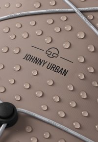 Barna szövet, kiemelkedő, texturált pöttyökkel és vízcseppekkel. Tartalmaz egy fekete "JOHNNY URBAN" logót és szürke díszkábelt fekete állítóval.