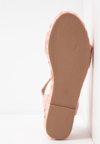 Sandales tissées roses avec une semelle en caoutchouc texturée, présentant une adhérence à motifs et un design à bout ouvert.