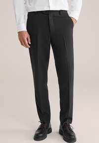 Fekete szabott nadrág, lapos elülső résszel, oldalzsebekkel és övhurkokkal. Az anyag diszkrét textúrával rendelkezik, barna öltönycipőkkel párosítva.