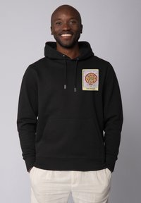 Sweatshirt à capuche noir avec poche avant, présentant une patch graphique de pizza colorée sur le côté gauche de la poitrine. Fabriqué en tissu doux avec une finition texturée.