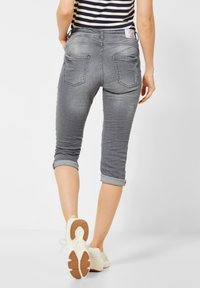 Jeans gris cortos con un diseño ajustado, puños enrollados y bolsillos traseros. La tela tiene una textura suave y ligeramente desgastada.