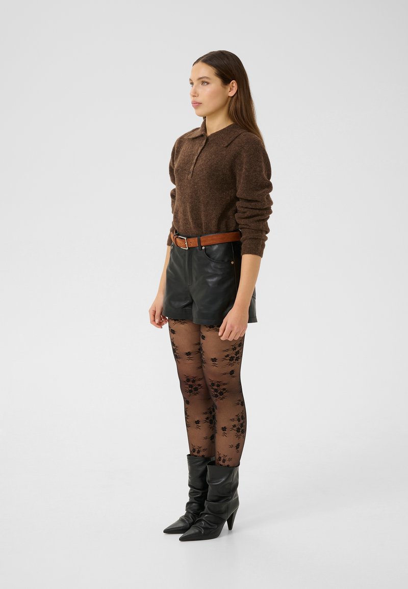 Brown knit sweater with a collar, paired with black leather shorts, floral-patterned tights, and pointed black ankle boots.