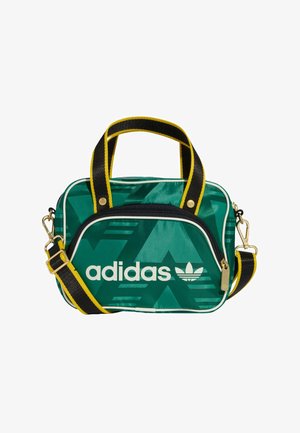 Borsa in nylon verde con design geometrico, caratterizzata da un logo "adidas" bianco, zip nera e tracolla regolabile con dettagli gialli.