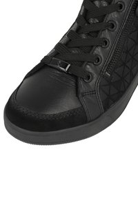 Baskets noires avec une combinaison de cuir lisse et de tissu texturé, motif géométrique, fermeture à lacets et détail de fermeture éclair sur le côté.