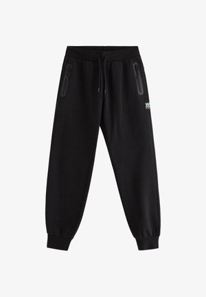 Czarne spodnie dresowe z sznurkiem w pasie, zapinanymi na zamek kieszeniami po obu stronach, elastycznymi mankietami oraz małym białym logo na prawym udzie.
