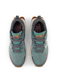 Zapatillas deportivas con upper de malla transpirable en azul verdoso y gris, con cordones decorativos, suela acolchada y acentos texturizados.