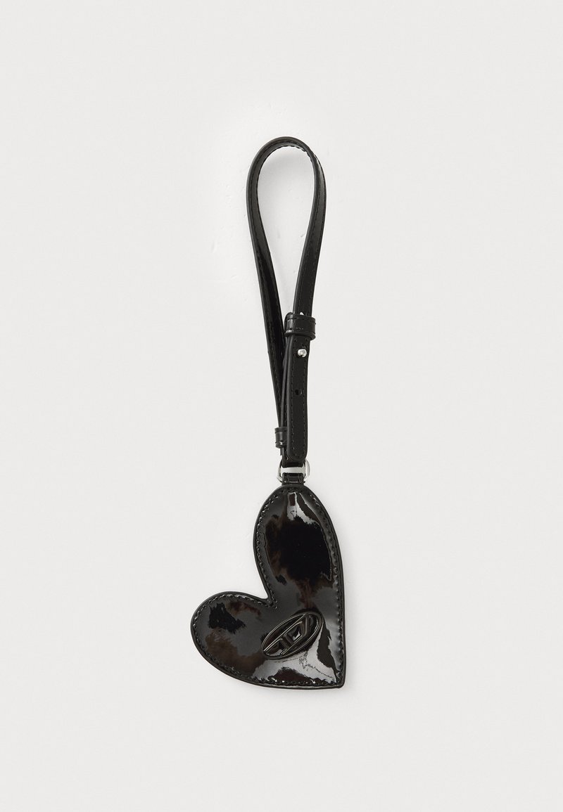 Black patent leather heart-shaped bag with a smooth texture, featuring a strap for hanging. The interior includes a contrasting design detail.