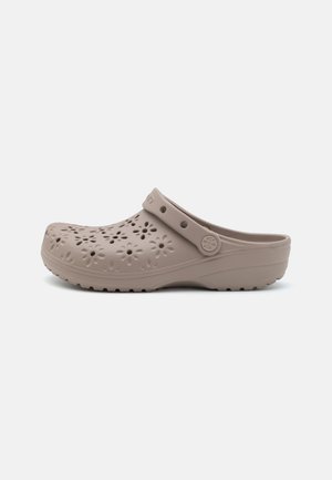 Zoccoli in resina beige con motivo floreale intagliato, forma sagomata e una fascia per una calzata sicura. Suola testurizzata per aderenza e trazione.