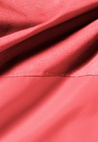 Tessuto rosso caratterizzato da una superficie liscia e lucida con una leggera lucentezza, che mostra pieghe e onde, passando da una tonalità più scura a una più chiara.