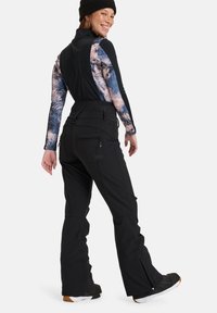 Zwarte sneeuwbroeken met een elastische taille, ritszakken en taps toelopende benen. Het model draagt een langarmtop met een blauw en roze ontwerp.