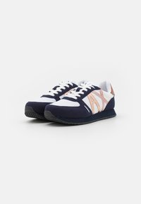 Navy and white athletic shoes with a suede and mesh upper, featuring rose gold accents and a textured rubber sole. Laced design.