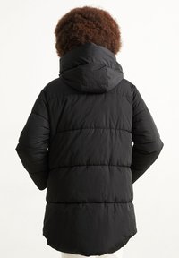 Czarna ocieplana kurtka z kapturem, z poziomym pikowaniem, gładką teksturą i nieco dłuższym tyłem dla dodatkowej osłony.