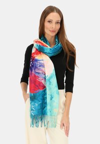 Kolorowy szalik w odcieniach niebieskiego, czerwonego i różowego z ozdobnymi frędzlami. Wykonany z miękkiego materiału, elegancko ułożony wokół szyi.