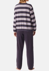 Stribet pullover i marineblå og lavendel nuancer, lavet af blødt stof. Afslappet pasform med ribbede manchetter og talje, parret med matchende marineblå bukser.