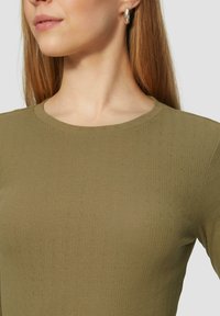 Olivgrüner, gerippter Pullover mit rundem Ausschnitt und dezenter strukturierter Musterung mit kleinen Punkten, gefertigt aus weichem, dehnbarem Stoff.