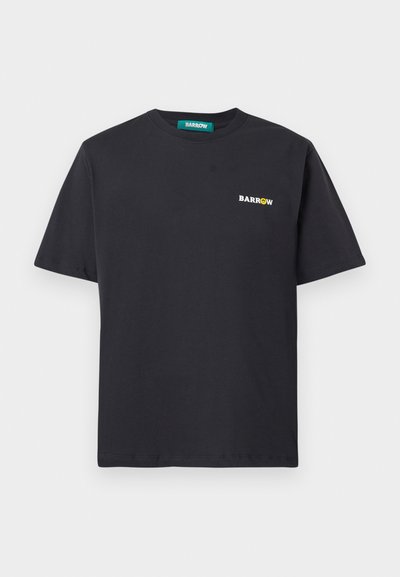 T-shirt di cotone nero con maniche corte e colletto rotondo. Presenta un piccolo logo bianco con testo giallo accentato sul lato sinistro superiore.