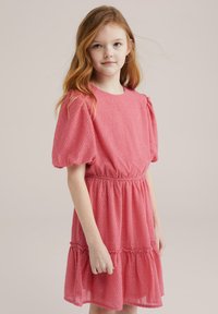 Vestido rosa de mangas abullonadas con tejido texturizado, cintura ajustada y falda en capas. Presenta un escote redondo y un sutil patrón de puntos.