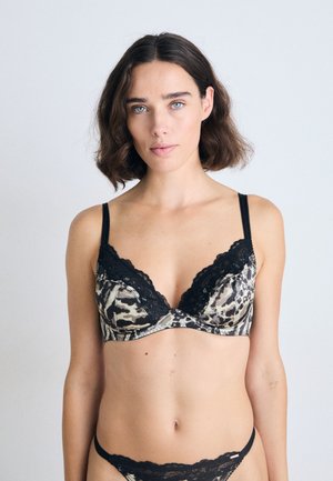 Bralette à dentelle en tissu imprimé animal, avec des bretelles noires, un décolleté plongeant et des bonnets structurés. Motif texturé sur l'ensemble.