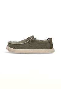 Zapatilla de lona verde oliva con una parte superior texturizada, suela trenzada de color claro en contraste y un detalle de cordones en la parte delantera. El interior cuenta con un forro estampado.