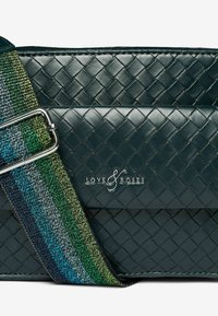 Borsa a tracolla in pelle intrecciata verde con una cintura a righe multicolore. Decorata con il nome del marchio "LOVE & ROSES" sul davanti.