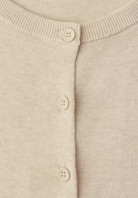 Primo piano di un cardigan beige lavorato a maglia con tre bottoni rotondi e colletto a coste.