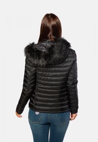 Doudoune noire avec une finition texturée, dotée d'une capuche en fausse fourrure. Design ajusté avec des sections matelassées horizontales et des manches longues.