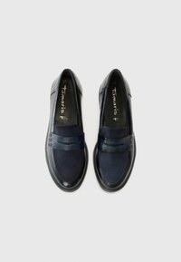 Een paar marineblauwe vrouwenloafers met suède en krokodillenleer texturen, platte zolen en "tamaris" merk binnenin.