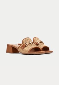 Sandales à glissière tissées marron avec un talon bloc moyen, présentant un accent métallique décoratif et un design à bout ouvert pour la respirabilité.