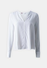 Vit långärmad blus med V-ringning och centralt sömdetalj. Tillverkad av ett mjukt tyg, med smala manschetter och en avslappnad passform.