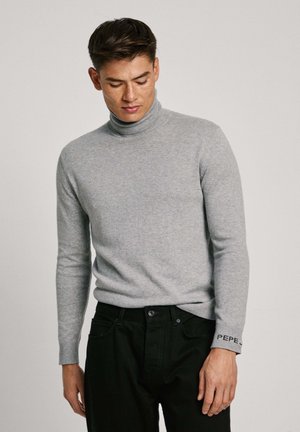 Maglione grigio a collo alto realizzato in un morbido tessuto a maglia, con un design aderente e dettagli neri sui polsini con testo ricamato.