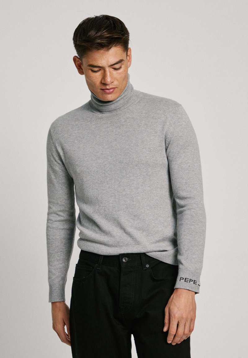 Szary sweter w serek wykonany z miękkiej dzianiny, charakteryzujący się dopasowanym krojem oraz czarnymi akcentami na mankietach z haftowanym tekstem.