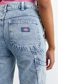 Lyseblå denim cargo-bukser med en baklomme og et rødt, gult og blått "Dickies"-logo-patch. Teksturert stoff med en avslappet design.