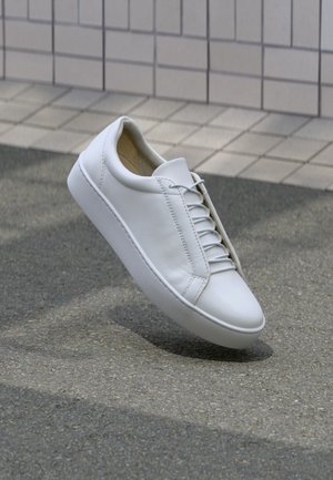 Witte lederen sneaker met een ronde neus, platte zool en zes paar veterogen. Glad textuur en minimalistisch ontwerp met stikseldetails.