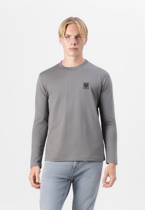 Long-sleeve gray t-shirt in soft material, featuring a small black logo patch on the chest, round neckline, and fitted design.