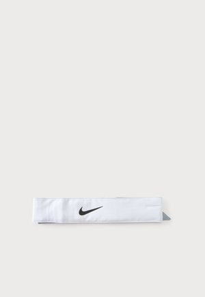 Un bandeau Nike blanc orné d’un logo Swoosh noir repose à plat sur un fond clair.