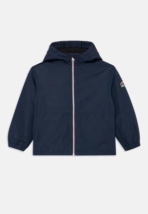 Veste imperméable bleu marine avec capuche, fermeture éclair à l'avant, poignets élastiques et détail de logo sur la poitrine. Texture lisse, design décontracté.