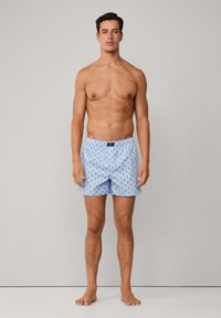 Muške plave pamučne kupaće hlače s ponavljajući malim uzorkom zvjezdica, elastičnim pojasom i kopčanjem na gumbe, s klasičnim krojem i laganom teksturom.