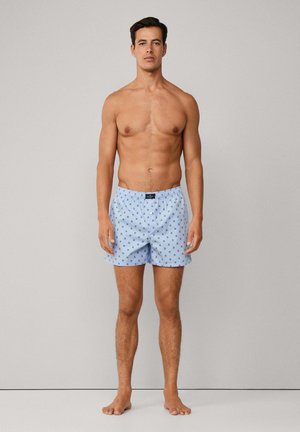 Muške plave pamučne kupaće hlače s ponavljajući malim uzorkom zvjezdica, elastičnim pojasom i kopčanjem na gumbe, s klasičnim krojem i laganom teksturom.