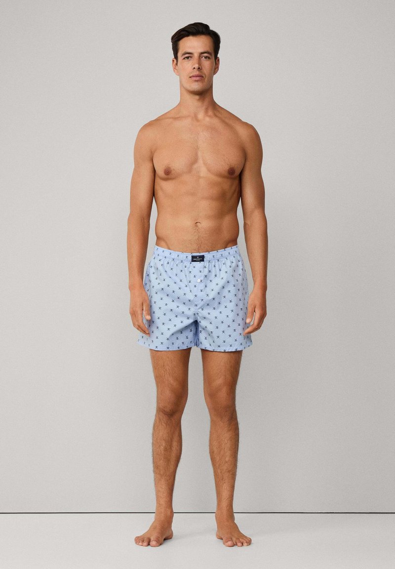 Muške plave pamučne kupaće hlače s ponavljajući malim uzorkom zvjezdica, elastičnim pojasom i kopčanjem na gumbe, s klasičnim krojem i laganom teksturom.