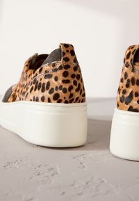 Baskets à imprimé léopard avec une tige texturée ressemblant à de la fourrure, des accents gris et des semelles épaisses en caoutchouc blanc. Dotées d'une languette à l'arrière.