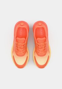 Sapatilhas laranja com um design em degradê, material em rede, forma arredondada, detalhes texturizados e atacadores, apresentando uma sola almofadada.