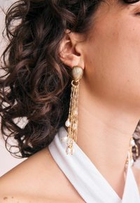 Gold-tone earrings featuring a striped round top and cascading chains adorned with small pearls, displaying intricate detailing and texture.