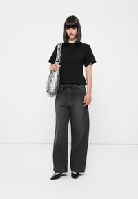 Black short-sleeve t-shirt, loose-fitting dark gray jeans, and black pointed flats. Holding a gray snake-print shoulder bag with a rounded shape.